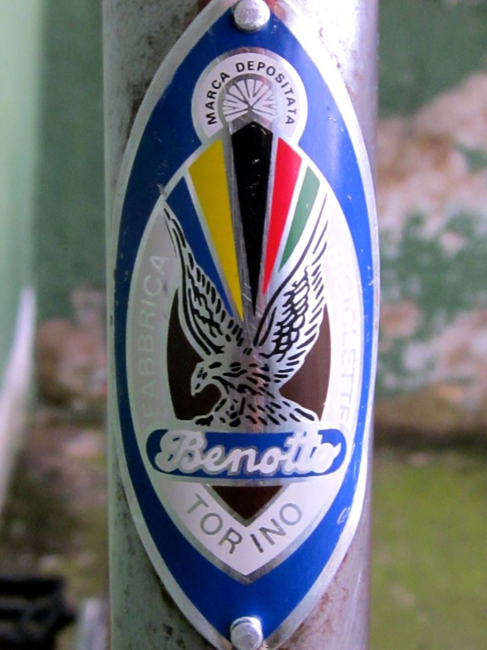 A period Benotto head badge on a frame: the crest with the eagle, rainbow stripes and Torino